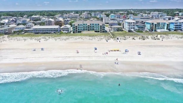 A coastal hotel with multiple buildings, a sandy beach, and ocean views.