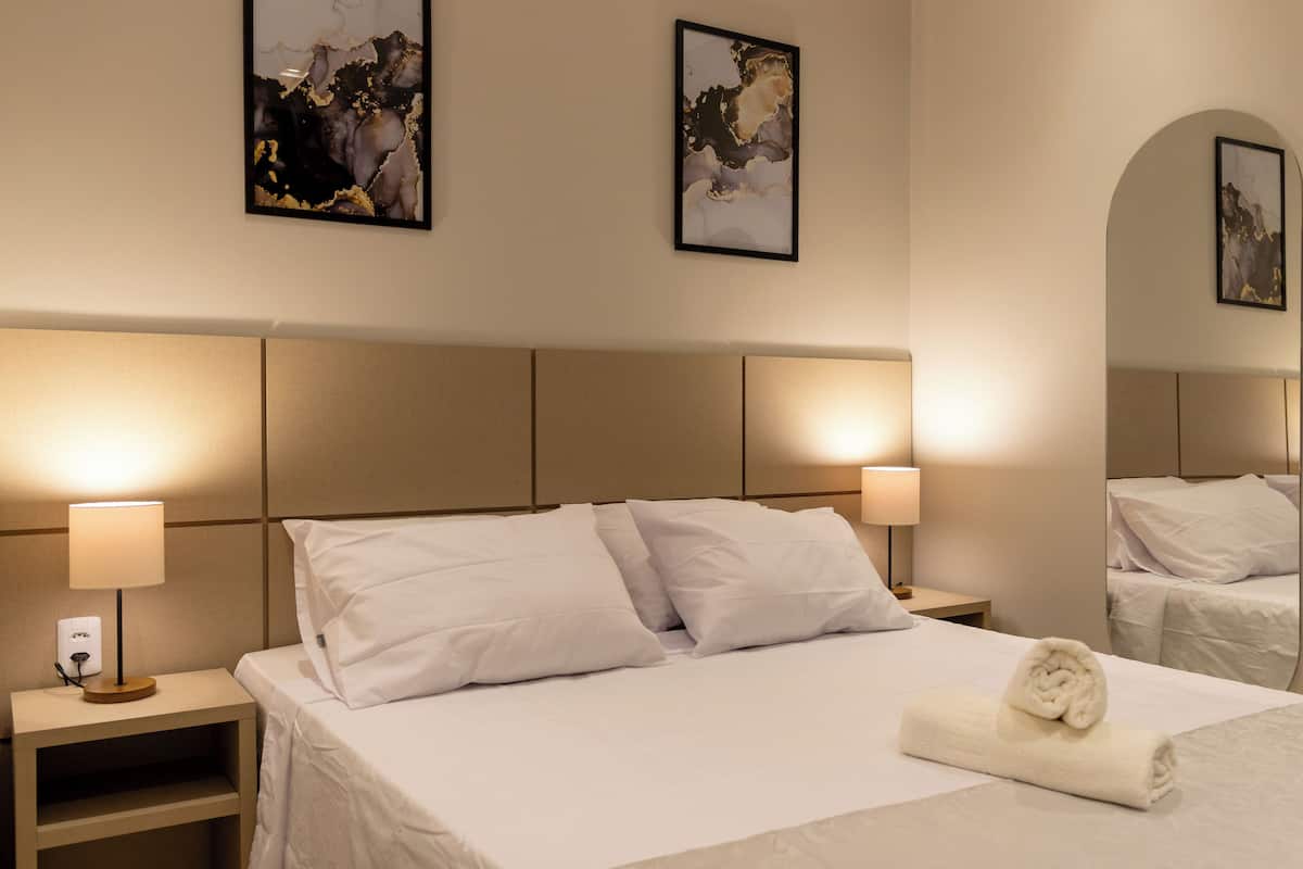 Ett hotellrum med en stor säng, två sänglampor och två inramade konstverk på väggen.