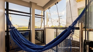 A hammock suspended between windows with a view of a building and power lines. - Aira Hotel (Sobral)