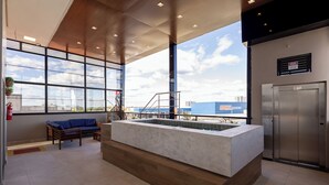 A modern interior with a large window, a reception desk, and a staircase leading to an upper level. - Aira Hotel (Sobral)
