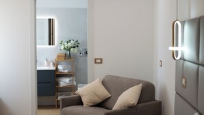 A modern bedroom with a grey sofa, a bedside table, and a mirror. - Gold Leaf Sicily "Superior Triple Room" Taormina center (Taormina)