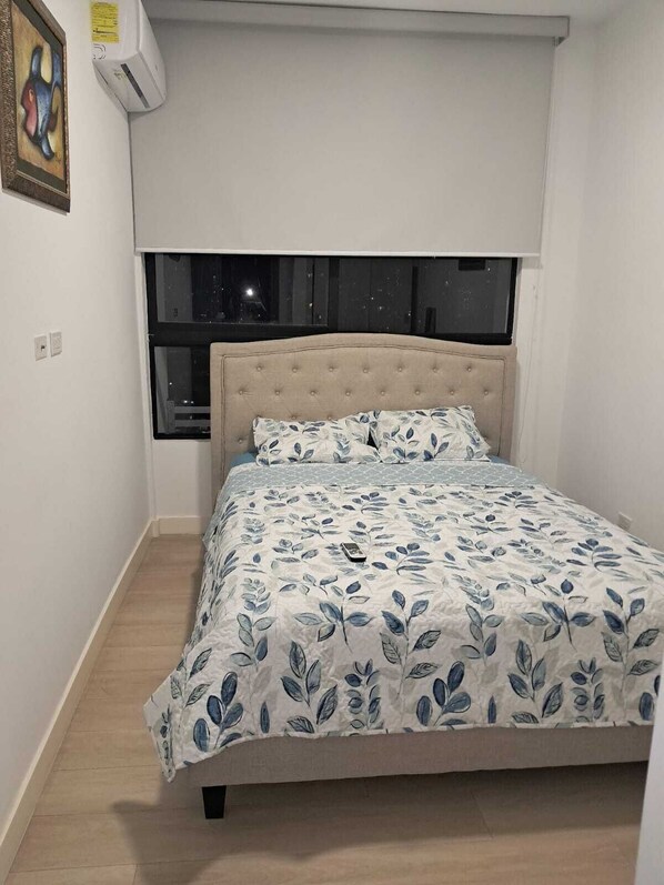 Une chambre à coucher avec un lit, une fenêtre et un appareil de climatisation.