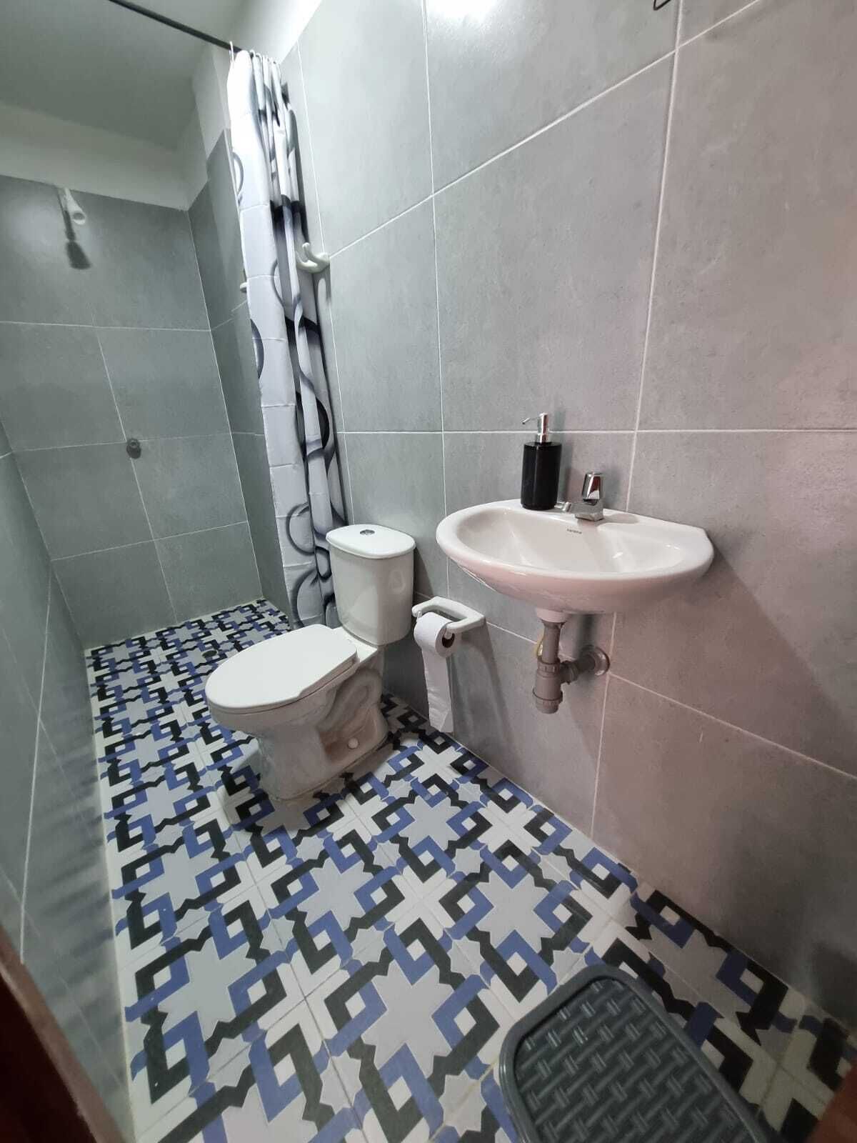 Un baño con inodoro, lavamanos y baldosas de suelo con diseño.