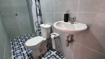 Un baño con inodoro, lavamanos y baldosas de suelo con diseño.