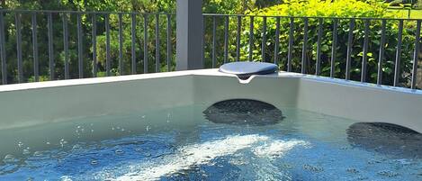 Un jacuzzi con vistas a un paisaje verde exuberante y una montaña al fondo.