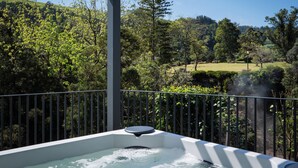 A hot tub with a view of a lush garden and hills. - Casa Nas Caldeiras (Povoacao)