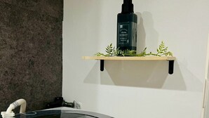 A washing machine with a control panel and a shelf above it holding a bottle of detergent.
