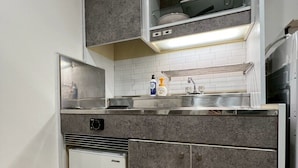 A compact kitchen with grey cabinets, a built-in oven, and a small refrigerator.