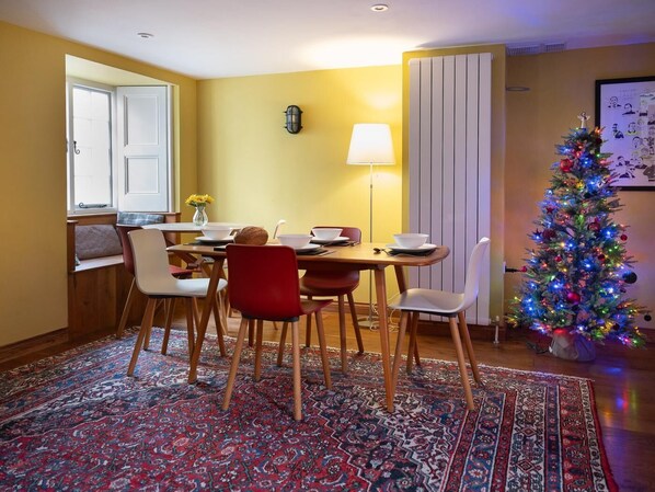 A dining area with a table, chairs, a Christmas tree, and a lamp.