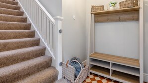 A staircase with carpeted steps, a white railing, and a checkered floor.