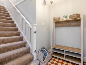 A staircase with carpeted steps, a white railing, and a checkered floor.