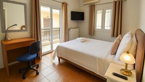 A hotel room with a bed, desk, chair, TV, and a balcony.