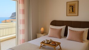 A hotel room with a bed, a bedside table with a lamp, a tray with breakfast items, and a view of the sea through a balcony. - Cosmo Room 2 | Seaside Retreat | Monemvasia Castle (Monemvasia)