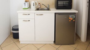 A compact kitchen with white cabinets, a microwave, a kettle, and a small refrigerator. - Cosmo Room 2 | Seaside Retreat | Monemvasia Castle (Monemvasia)