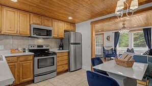 Una cocina con armarios de madera, electrodomésticos de acero inoxidable y un comedor con sillas azules y una mesa.