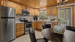 A modern kitchen with wooden cabinets, stainless steel appliances, and a dining area with a table and chairs.