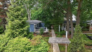 A residential property with a pathway leading to a house, surrounded by lush greenery and trees.