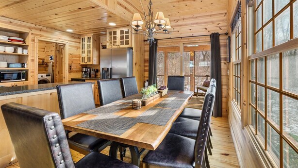 A wooden cabin interior with a dining area, kitchen, and large windows. - Timber Nest Goshorn lake dock, pool, town HOT TUB! (Saugatuck)