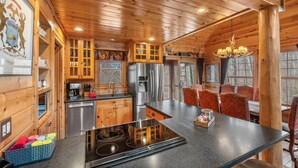 A wooden cabin interior with a kitchen featuring a stainless steel refrigerator, a built-in stove, and wooden cabinets.