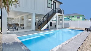 A modern house with a swimming pool, a covered patio with lounge chairs, and a staircase leading to the upper floor. - 🌊Private Pool | Steps to Beach | Ocean Oasis🌊 (Fort Myers Beach)