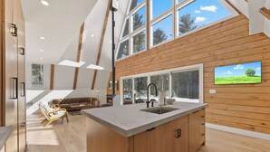 Una cocina moderna con una isla grande, paredes de madera y ventanas amplias que ofrecen vistas al exterior.