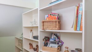 A bookshelf with books, a wicker basket, and decorative items. - Figgy Cottage (Ripon)