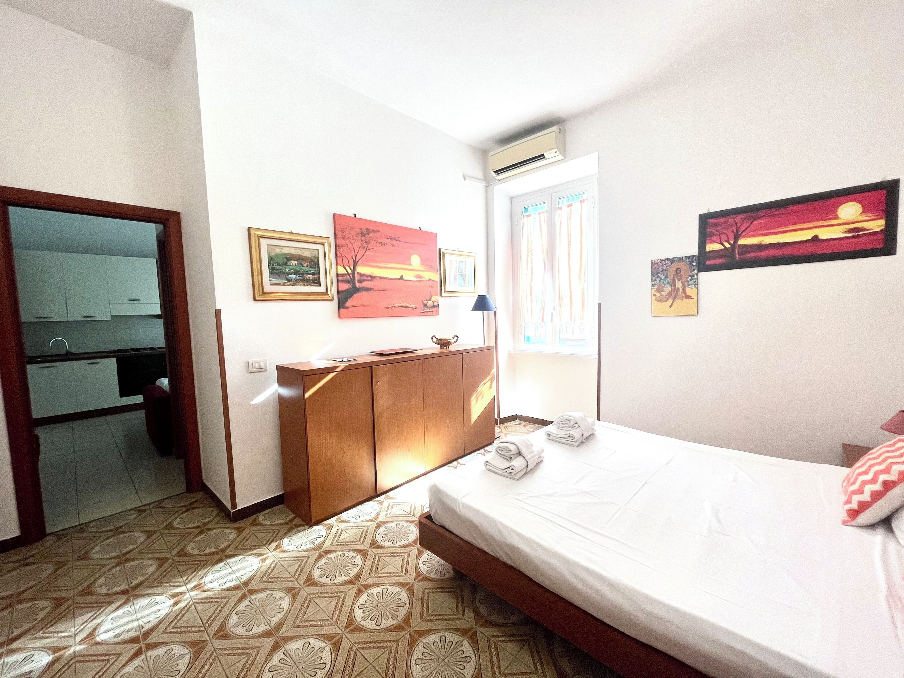 Ein Hotelzimmer mit Bett, Schreibtisch, Kleiderschrank und Bildern an den Wänden.