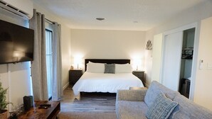 Une chambre d’hôtel avec un lit, un canapé, une télévision et une table de chevet.