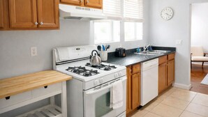 A modern kitchen with wooden cabinets, a white stove, and a black countertop. - Beautiful 1 Bdrm • Historical • Downtown (Salt Lake City)
