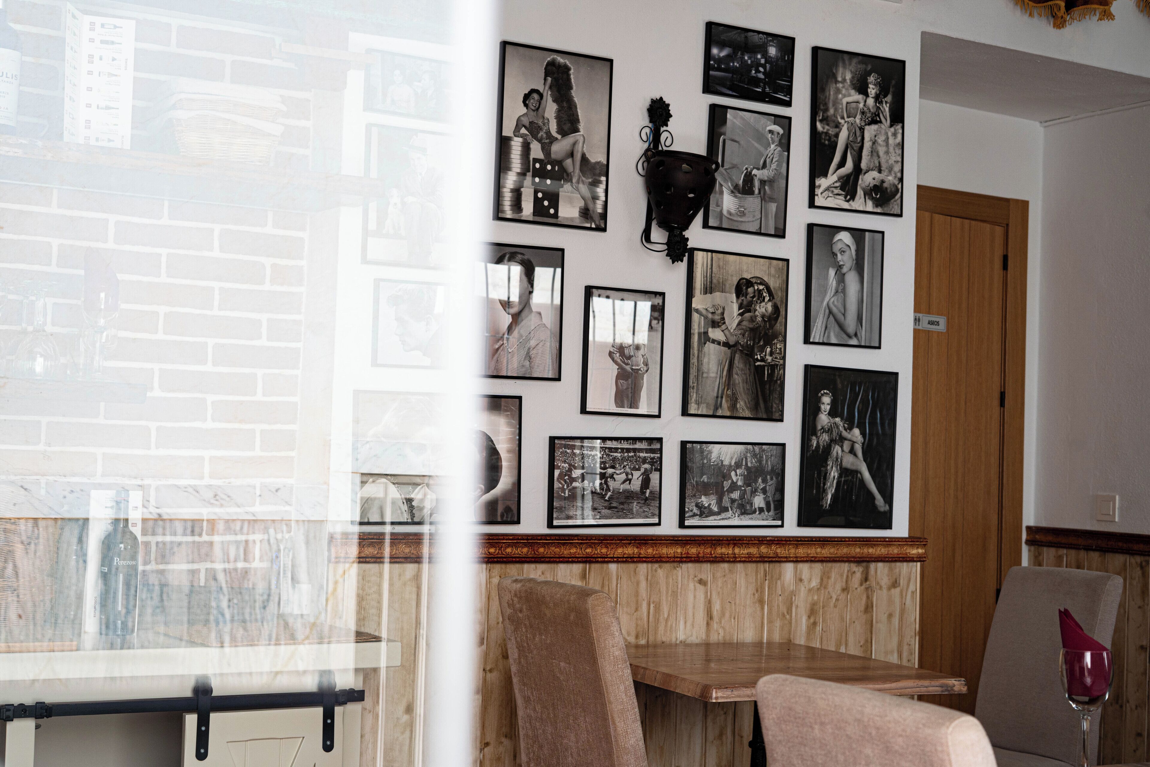 Un restaurante con pared de ladrillo, paneles de madera y una variedad de fotografías blanco y negro en la pared.