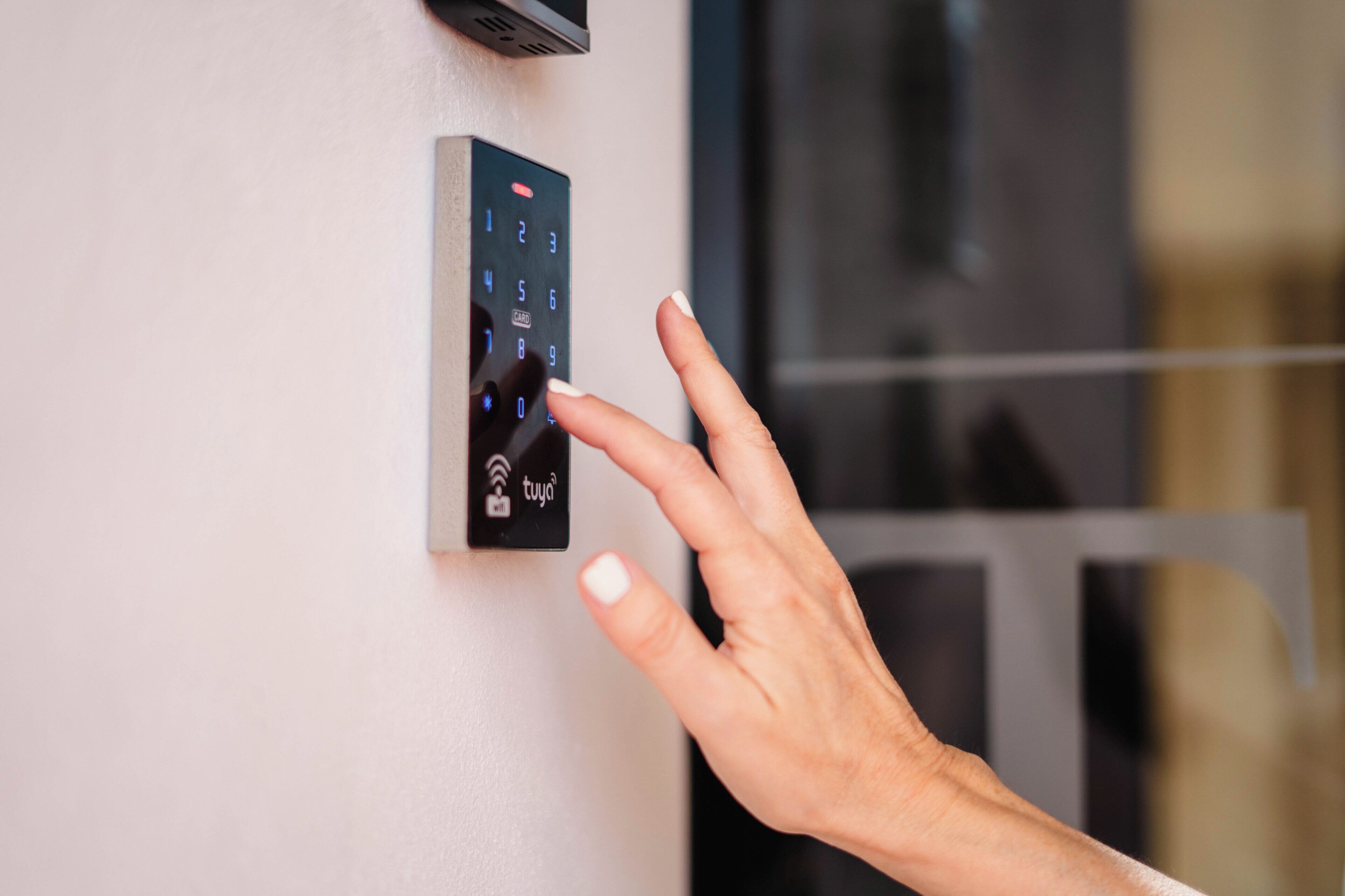 Una mano interactuando con un teclado digital fijado a la pared.