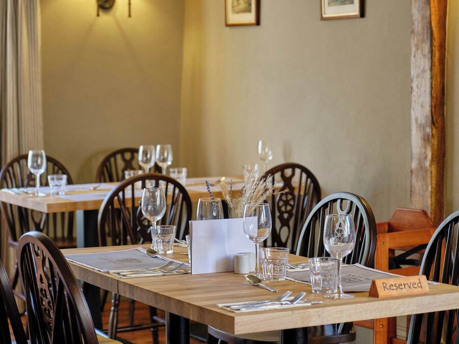A restaurant table set with wine glasses, cutlery, and a 'Reserved' sign.