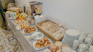 A buffet with various food items, including bread, pastries, and fruits, along with several cups and plates. - Guest House Stories (Beja)