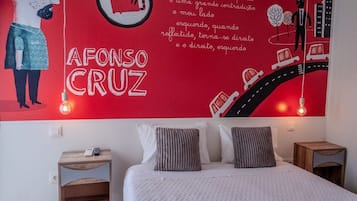A bedroom with a large wall mural, a bed with gray and white bedding, two bedside tables, and a nightstand.