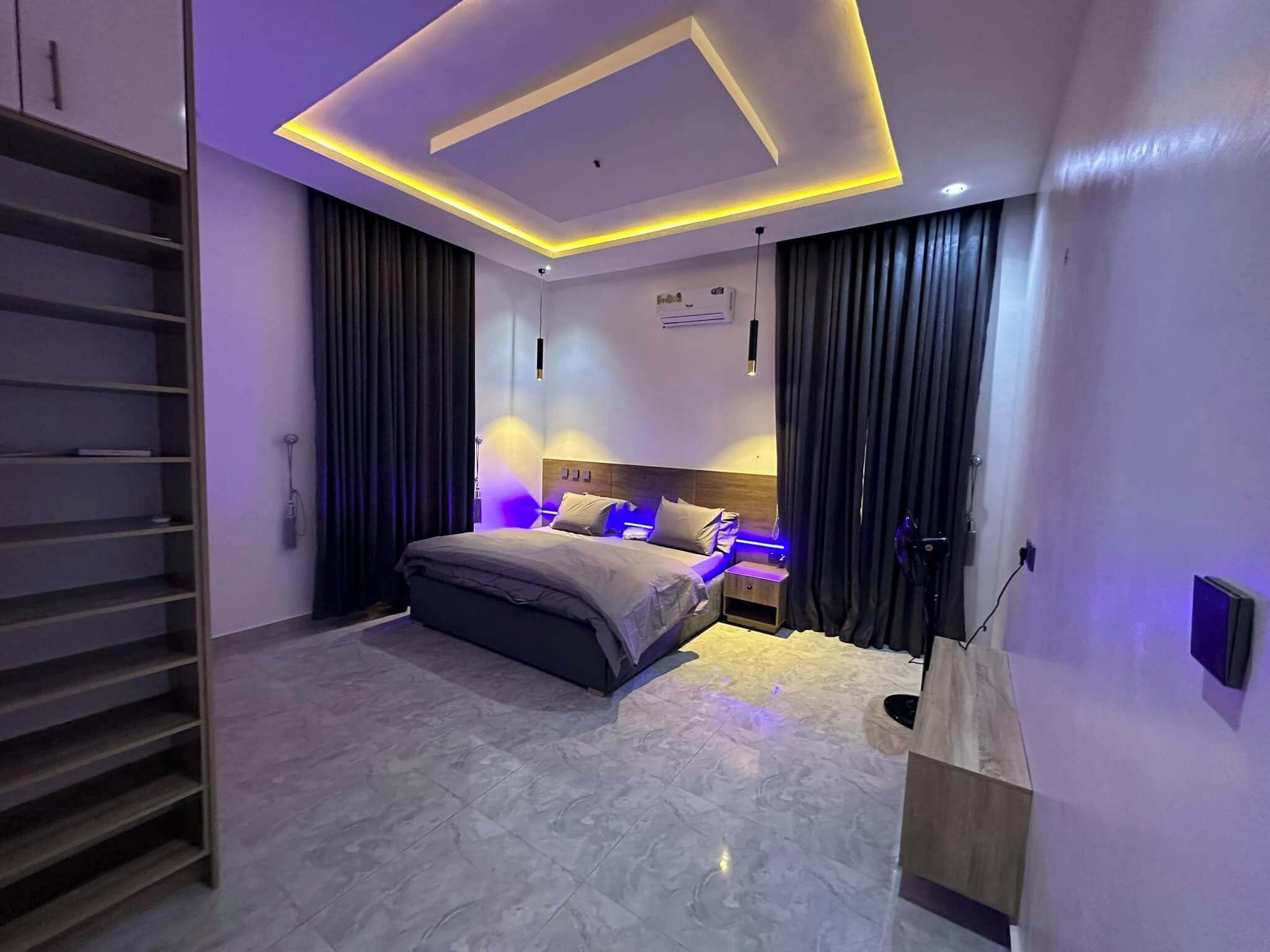 Une chambre moderne avec un lit, des étagères intégrées et un luminaire au plafond.
