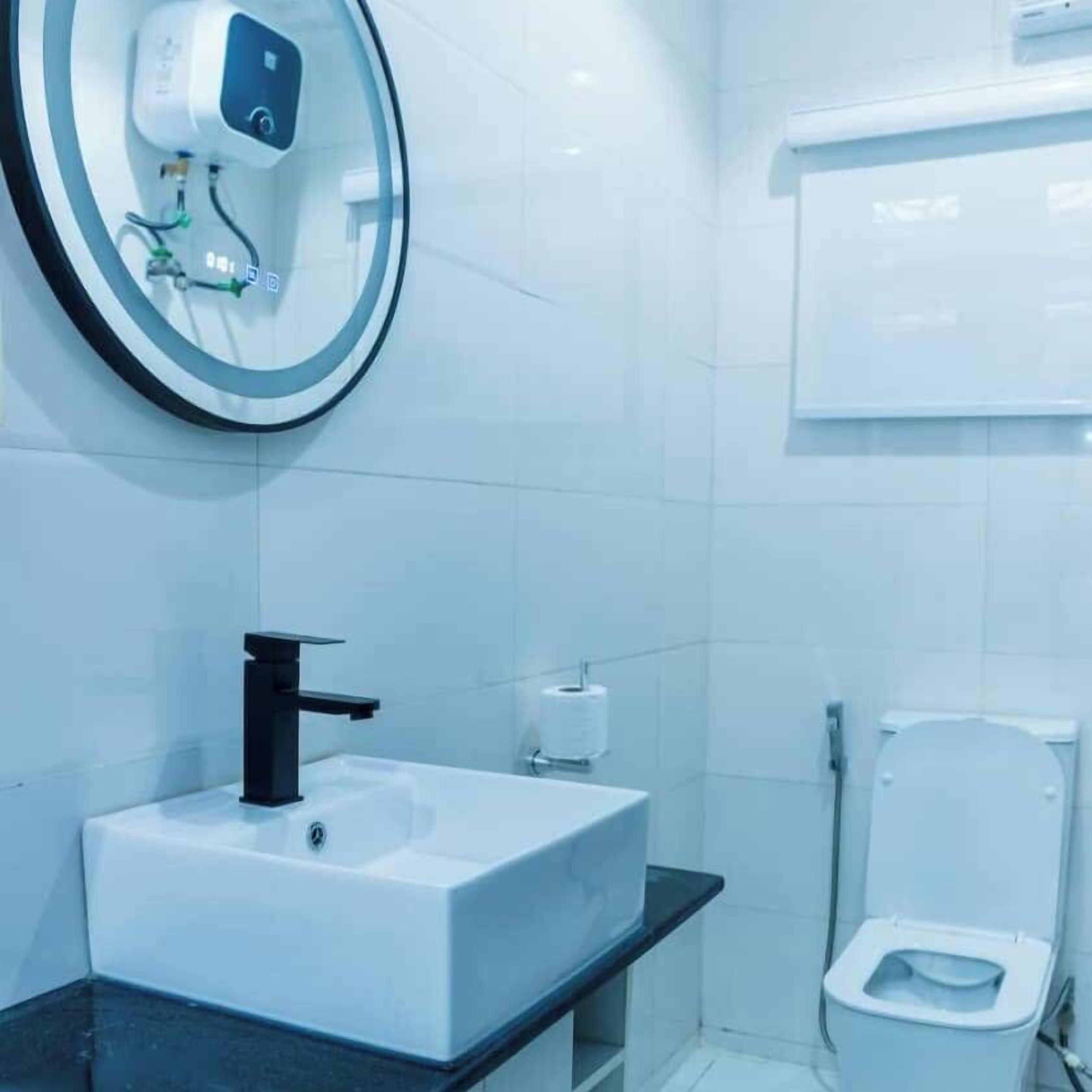 A modern bathroom with a white sink, black faucet, and a toilet.