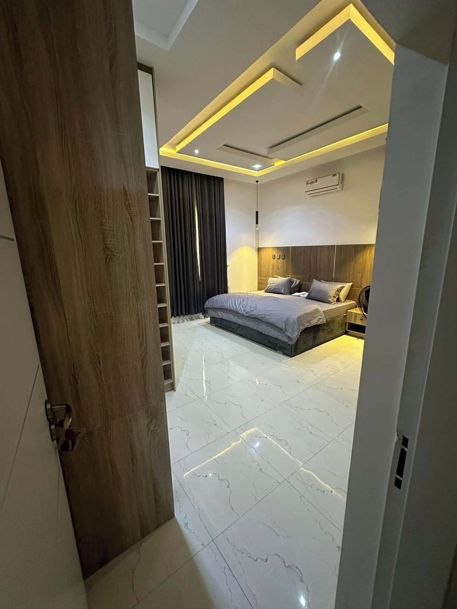 A modern bedroom with a bed, bedside tables, a wardrobe, and a ceiling with recessed lighting.