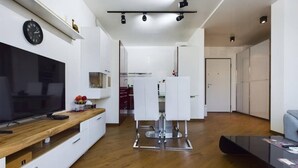 Een moderne keuken met witte kasten, een houten aanrecht en een eethoek met witte stoelen.