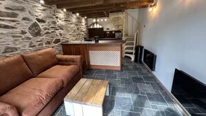 Ein modernes Wohnzimmer mit Steinwand, Ledersofa, Couchtisch aus Holz und Kamin.