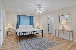 A bedroom with a bed, bedside lamps, a ceiling fan, a rug, a console table, and a framed picture on the wall. - ⛱️Dog Friendly-Close to Beach-Seaside Solace⛱️ (Destin)