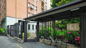 A covered bicycle parking area with a metal fence, a bicycle, and a building with balconies in the background. - Bright 1-br apartment in Porta Genova (Milan)