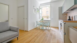 A modern kitchen with a dining area, a sofa, and a window with a view of buildings. - Bright 1-br apartment in Porta Genova (Milan)
