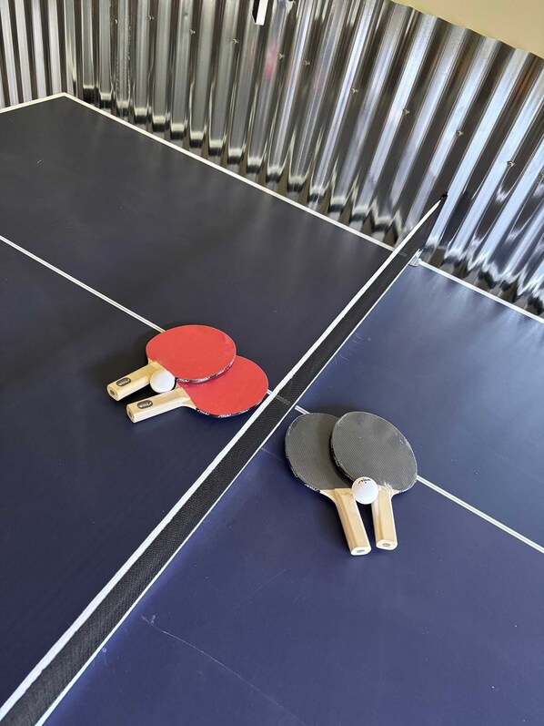 Ett bordtennisbord med två röda och två blå racketar samt en vit boll.
