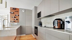 A modern kitchen with grey cabinets, a wooden wine rack, a coffee maker, and a kettle. - Giulia Prestige, apartment with Terrace Luxury & Comfort at the gates of Paris (Clichy)