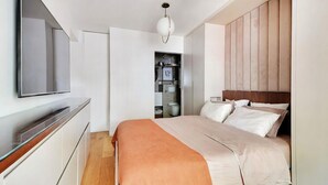 A modern bedroom with a bed, a television, and a wardrobe. - Giulia Prestige, apartment with Terrace Luxury & Comfort at the gates of Paris (Clichy)