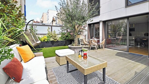 A modern outdoor patio with a sofa, chairs, a table, and a small garden area. - Giulia Prestige, apartment with Terrace Luxury & Comfort at the gates of Paris (Clichy)