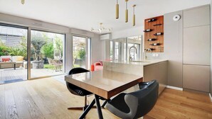 A modern kitchen with a wooden island, black chairs, and pendant lights. - Giulia Prestige, apartment with Terrace Luxury & Comfort at the gates of Paris (Clichy)
