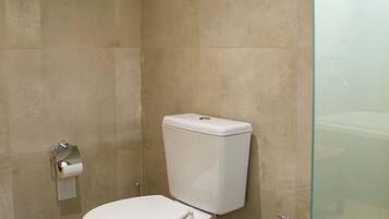 Un baño con inodoro, bidé y cabina de ducha de cristal.