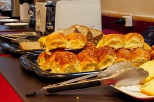 Una mesa de buffet con diversas opciones de panadería, incluyendo croissants y pan.