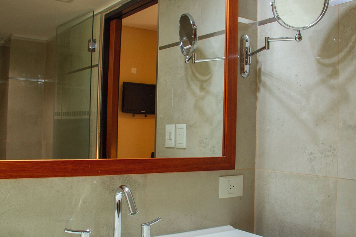 A bathroom with a large mirror, two sinks, and a wooden vanity.